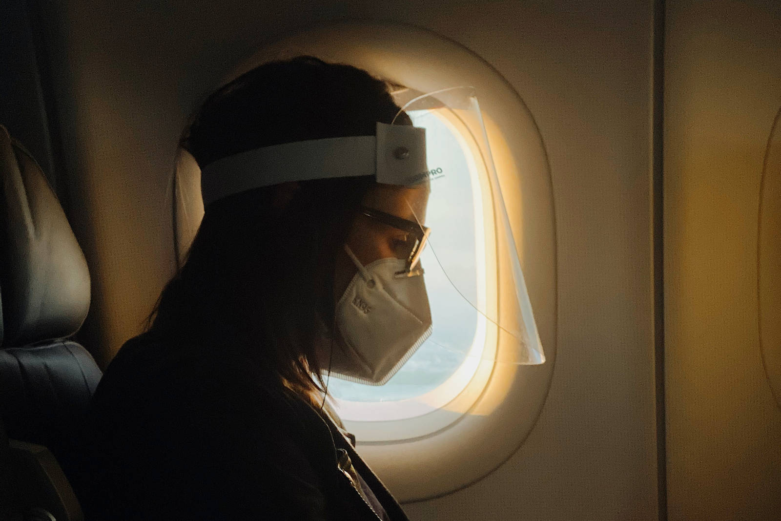 Mann mit Maske auf Reise im Flugzeug